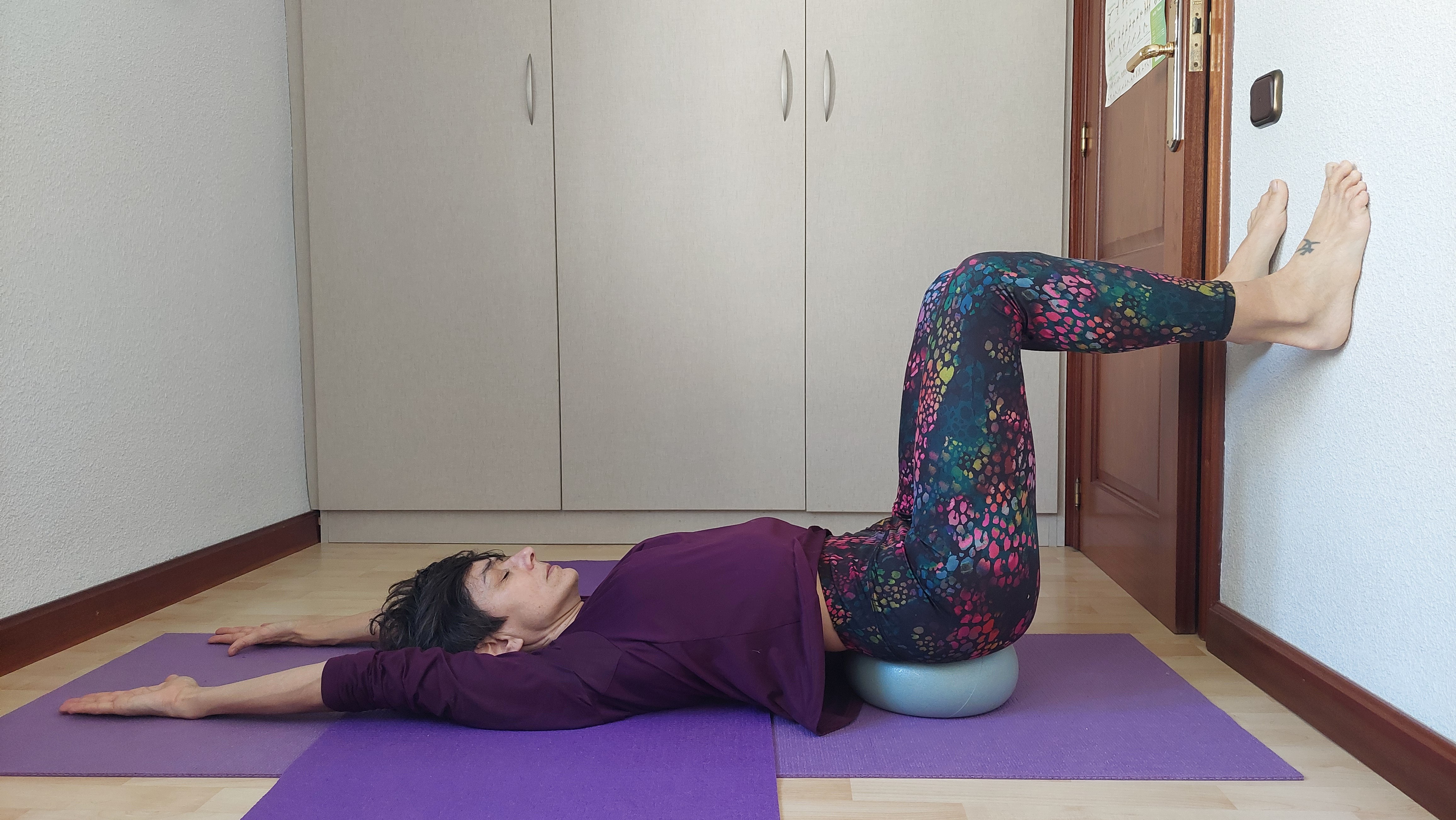 RODILLA DOBLADA CON TOBILLO APOYADO EN RODILLA CONTRARIA CON PELOTA PILATES BAJO NALGAS